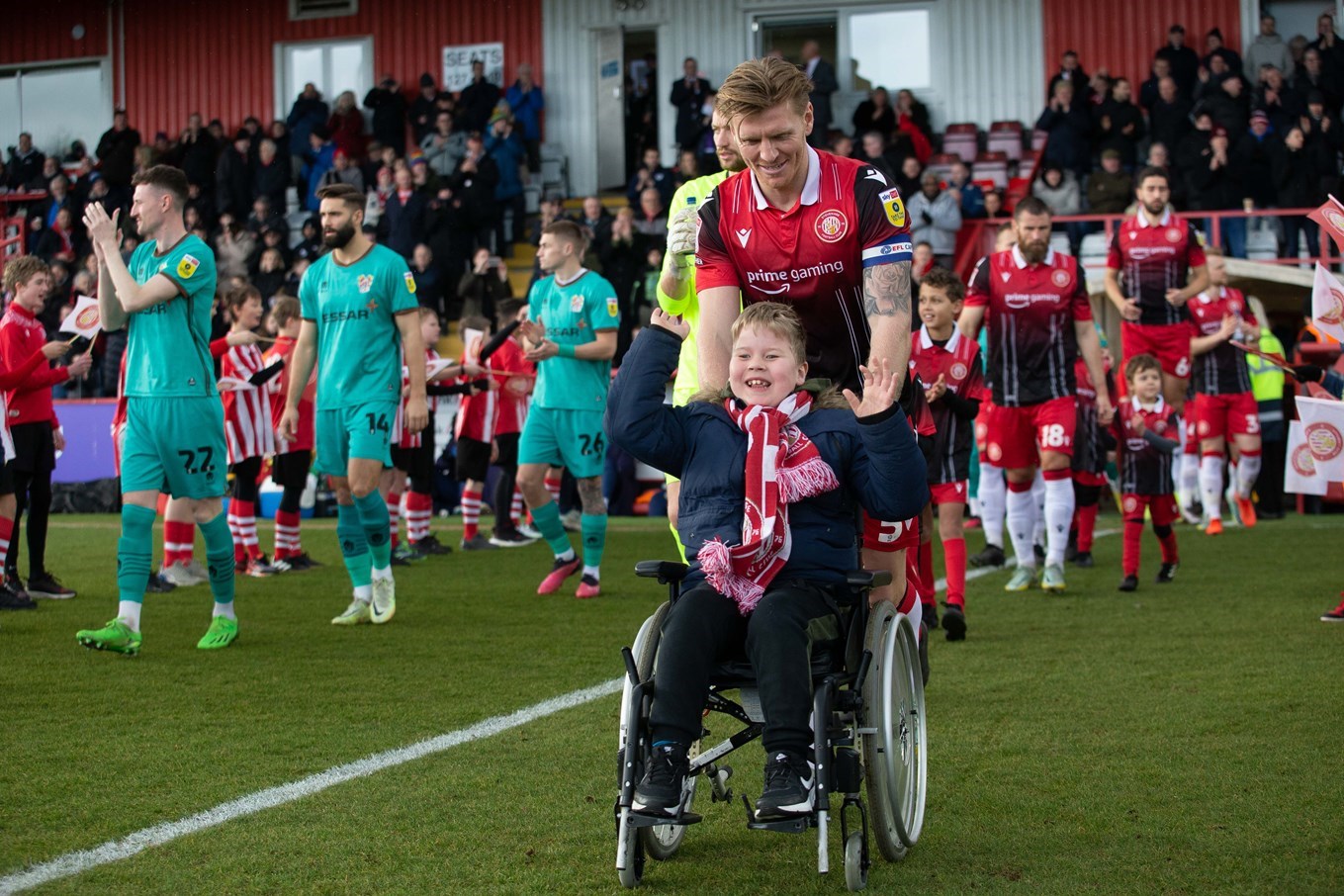 Wheelchair user Archie Riley leads out the Stevenage team vs Tranmere last season